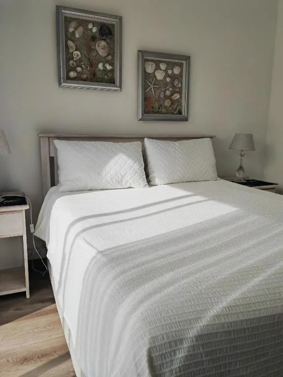 Neatly made bed with white and grey striped bedding and decorative coastal artwork