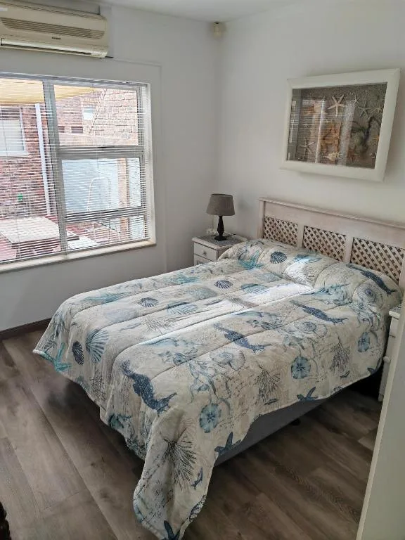 Bright bedroom with queen bed, coastal-themed bedding, and large window