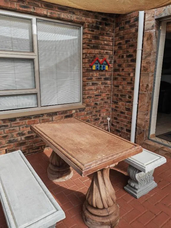 Brick-walled outdoor seating area with wooden table and cushioned benches