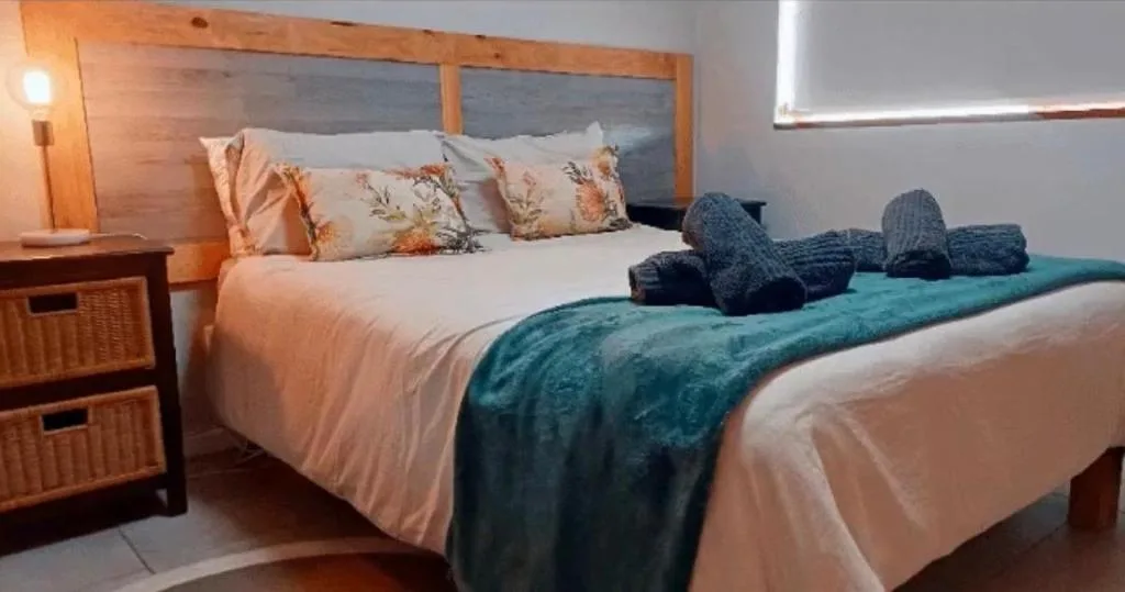 Spacious bedroom with queen bed, wooden headboard, and teal accents