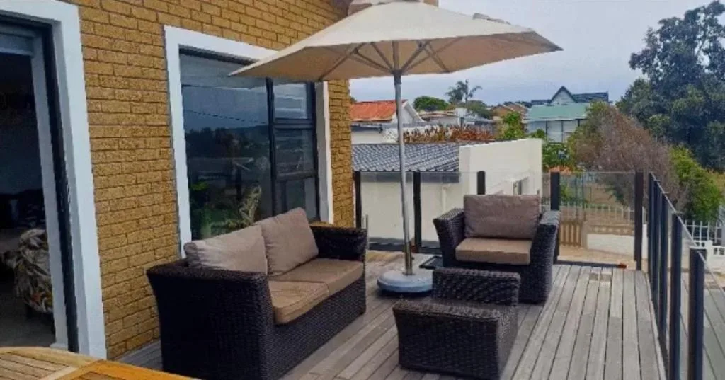 Spacious outdoor deck with rattan seating, umbrella, and neighborhood views