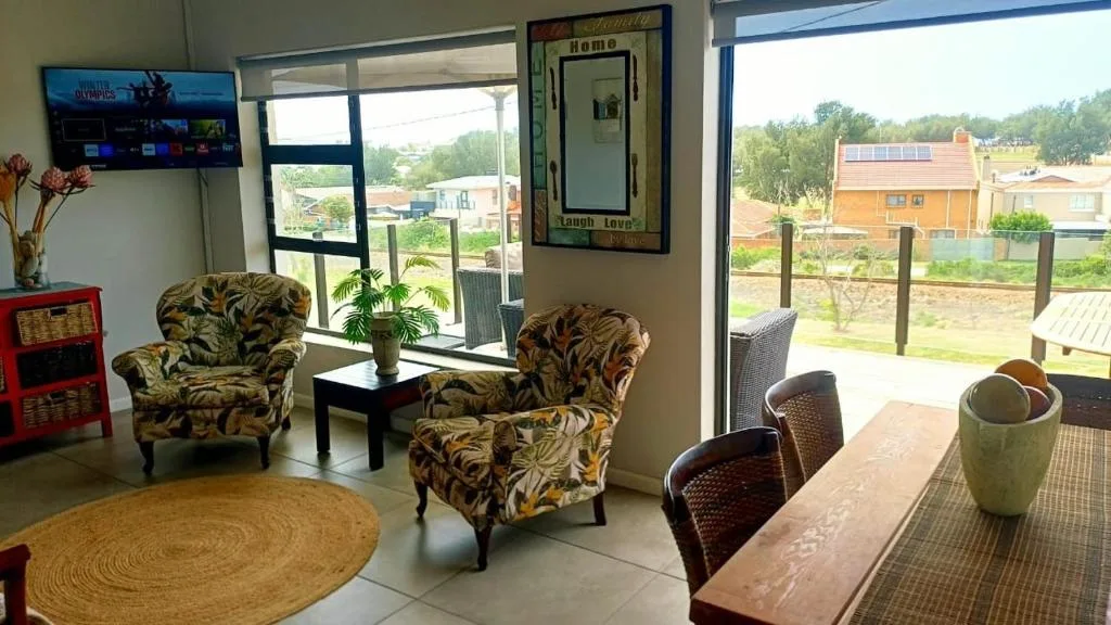 Open-plan lounge with patterned armchairs, TV, and garden views