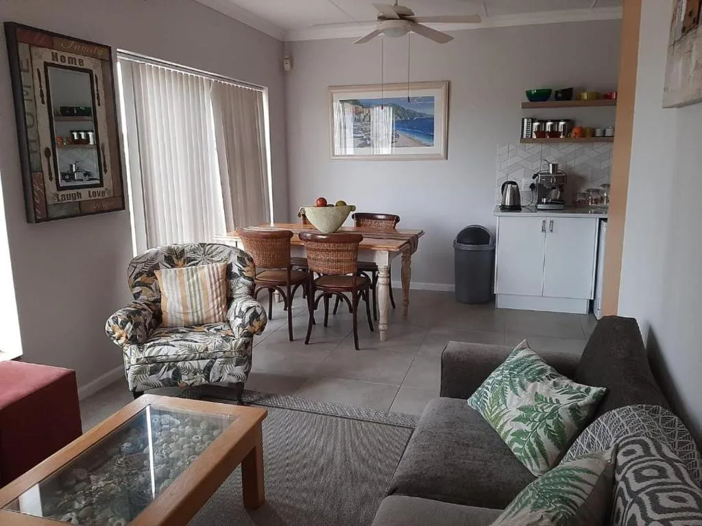 Open-plan lounge and dining area with sofa, armchair, and wooden dining table
