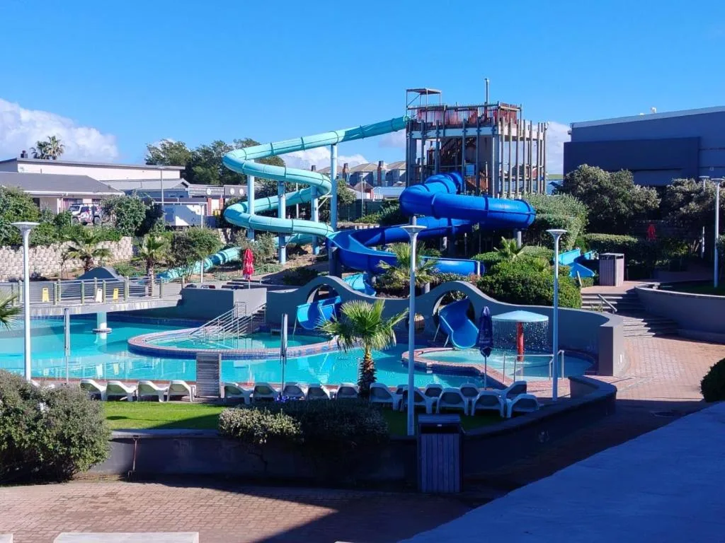 Bright blue water park with twisting slides and tropical landscaping