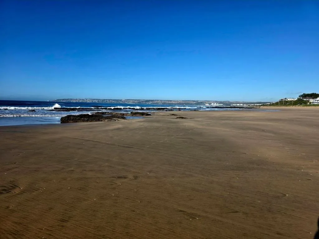 Expansive beach vista with rolling waves and coastal town shoreline