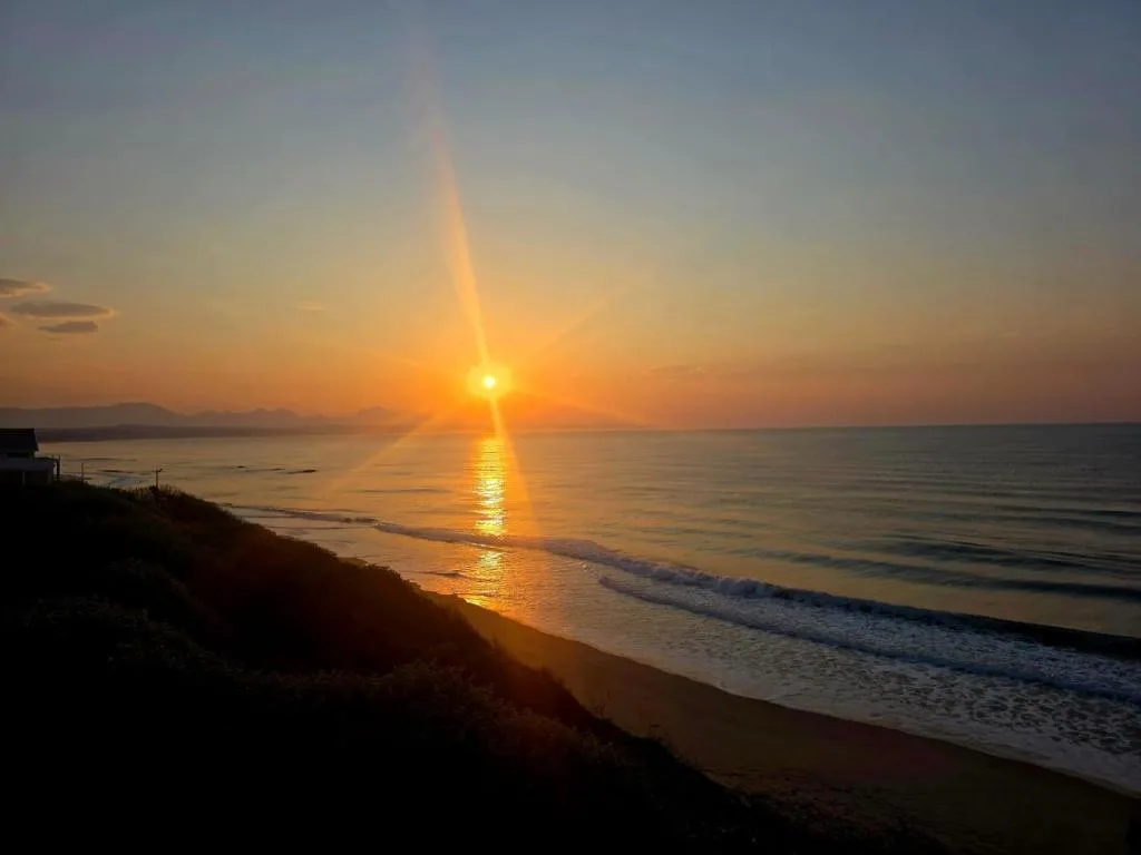 Golden sunset over calm ocean waters and sandy beach from property vantage point