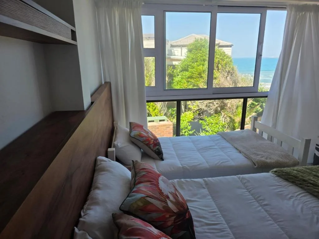 Bright bedroom with twin beds overlooking ocean and coastal garden route views