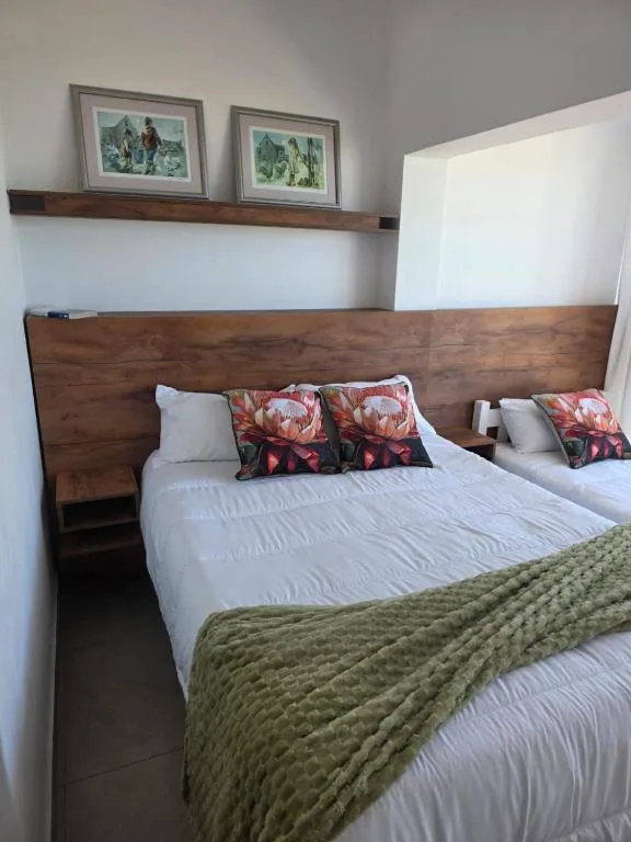 Spacious bedroom with wooden headboard, white bedding, and decorative floral pillows