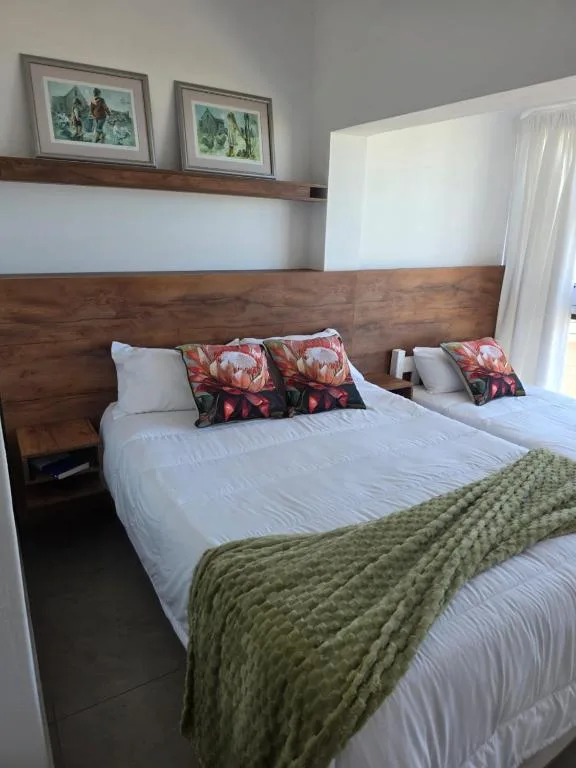 Spacious bedroom with wooden headboard and white bedding, floral cushions