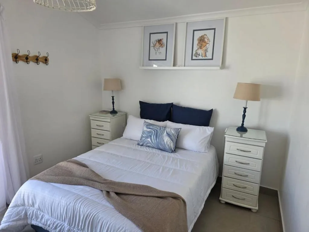 Bright bedroom with queen bed, navy pillows, matching nightstands and lamps