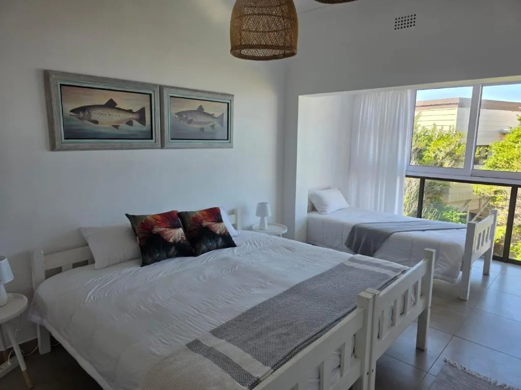 Bright bedroom with white bed, fish artwork, and balcony garden views