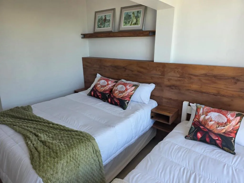 Twin bedroom with wooden headboard, white linens, and floral patterned pillows