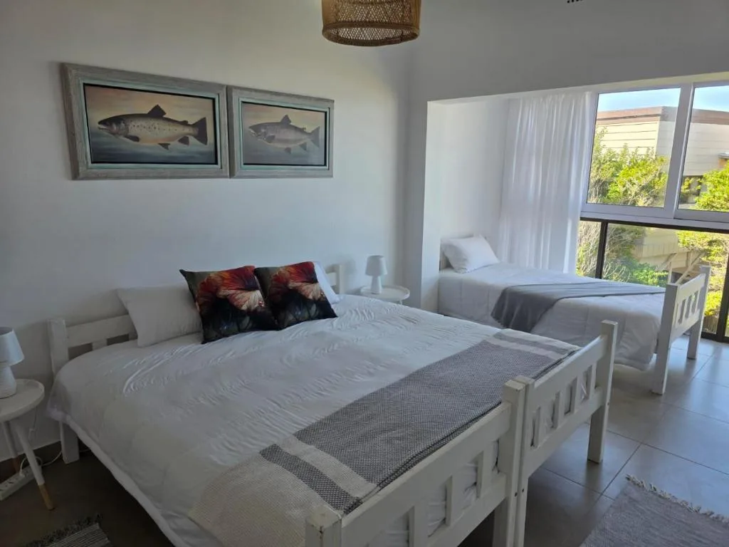 Bright bedroom with two white beds and fish artwork on walls