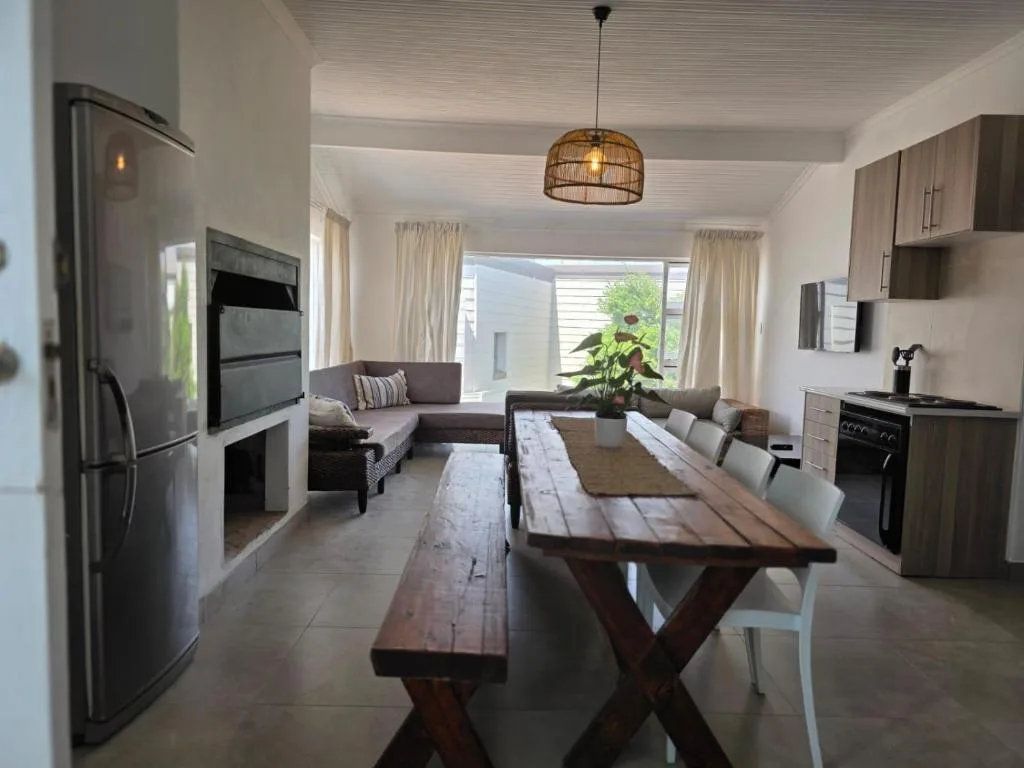 Open-plan dining area with wooden table, kitchen, and lounge visible