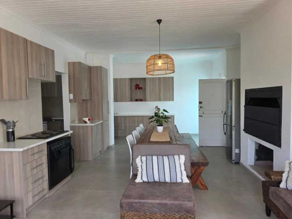 Open-plan dining and kitchen area with wooden table and striped cushioned seating