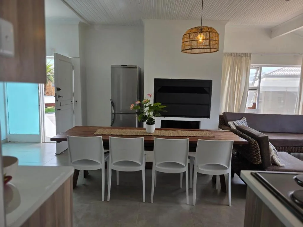 Modern dining area with wooden table and white chairs in open-plan living space