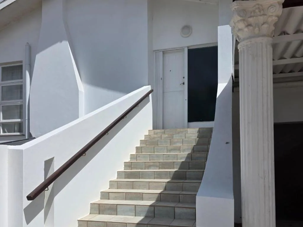 Outdoor staircase with handrail leading up white villa exterior