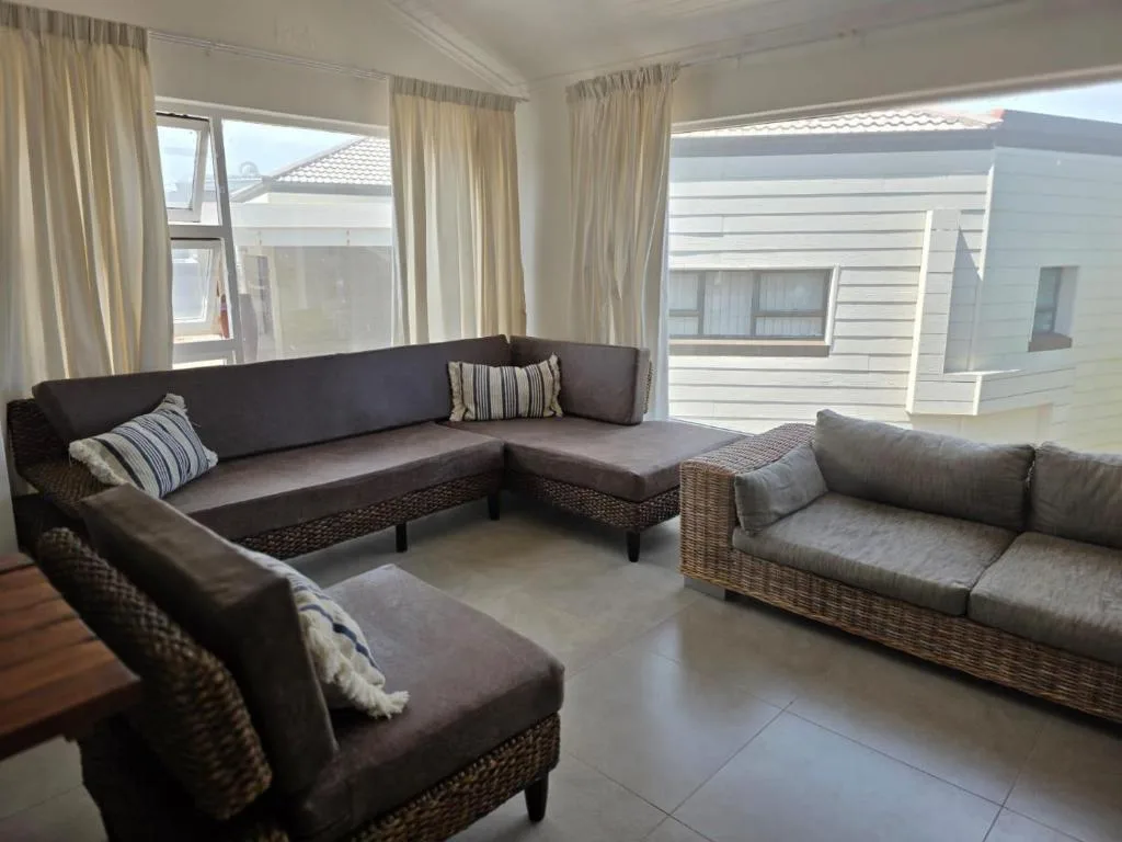 Spacious living area with dark sofas and wicker furniture overlooking garden