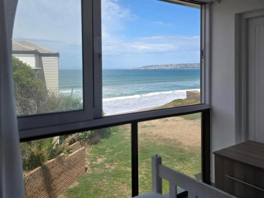 Ocean and beach views through large windows with coastal cliffs visible