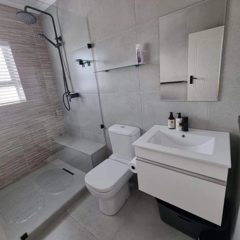 Modern bathroom with walk-in shower, white vanity, and toilet fixtures
