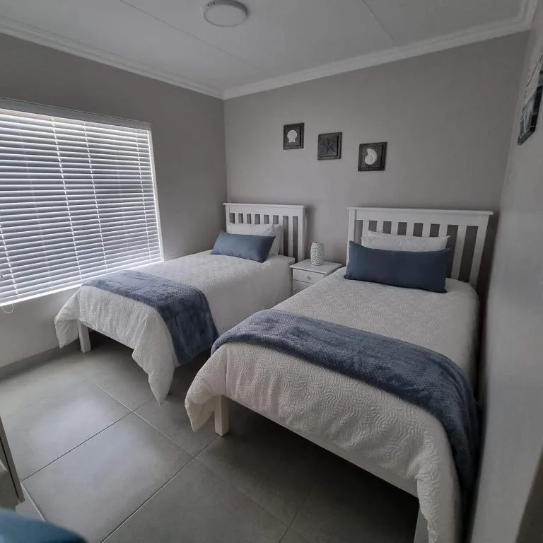 Twin bedroom with white frames and navy bedding, neutral walls, and natural light