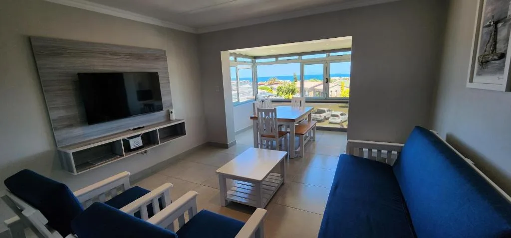 Modern lounge with blue sofa, wall-mounted TV, ocean view through large windows