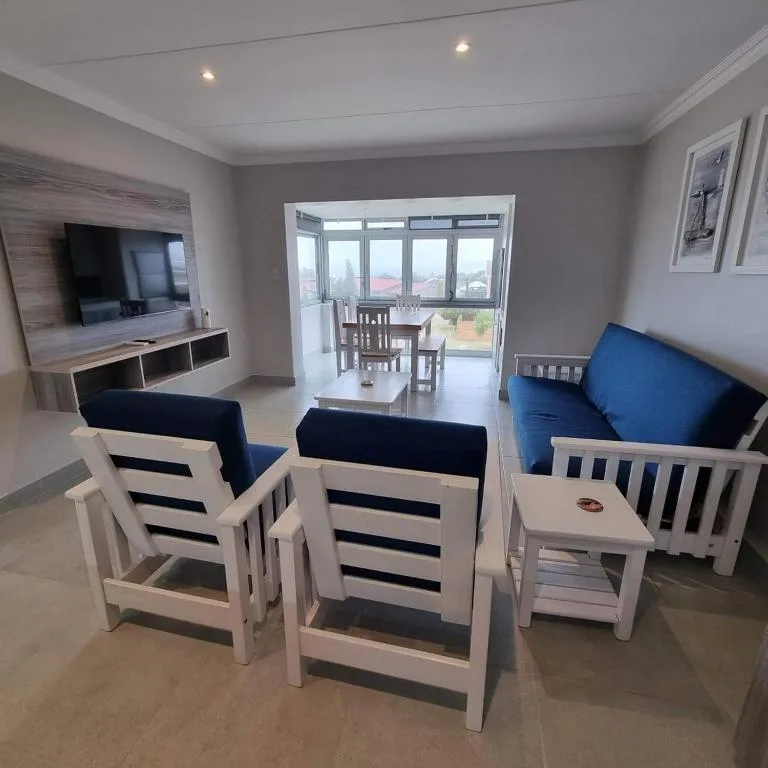 Spacious lounge with blue sofas, TV, and scenic mountain views through sliding doors