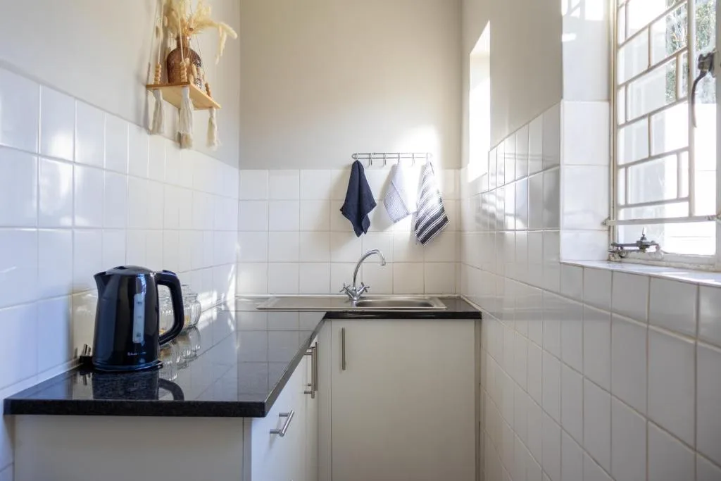 Clean bathroom with white tile walls, sink, and small window