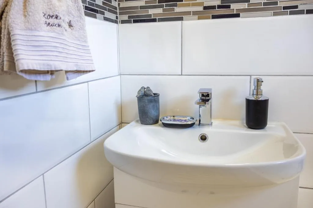 Modern bathroom vanity with white basin, decorative accessories, and subway tile