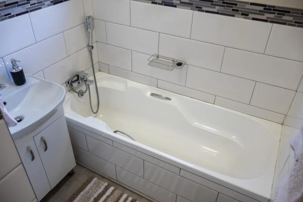Modern bathroom with white subway tiles, bathtub, and pedestal sink