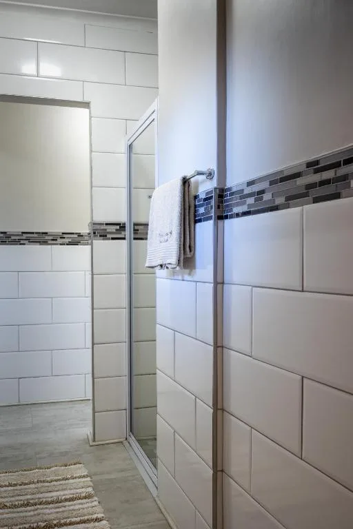 Modern bathroom with walk-in shower, white tile walls, and heated towel rack