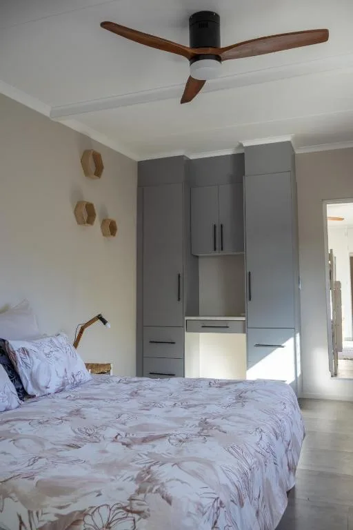 Bright bedroom with bed, ceiling fan, and gray built-in wardrobes