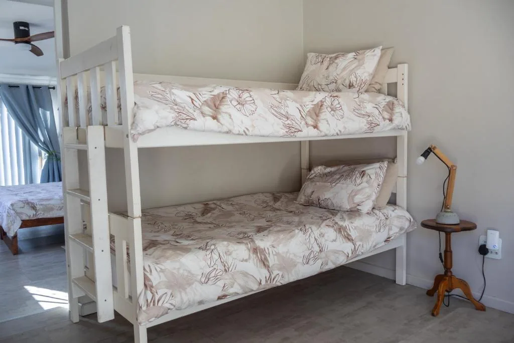 White wooden bunk beds with floral bedding in bright bedroom