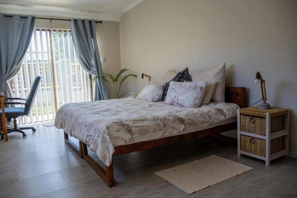 Spacious bedroom with wooden bed, patterned bedding, and balcony access doors
