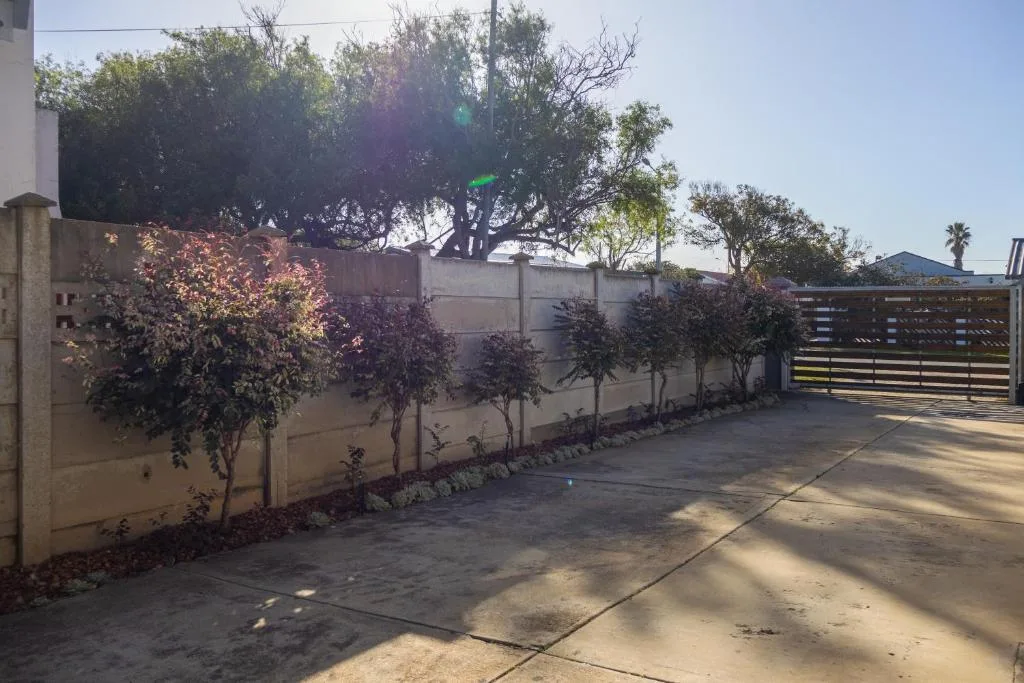 Gated driveway entrance with mature trees and landscaped garden