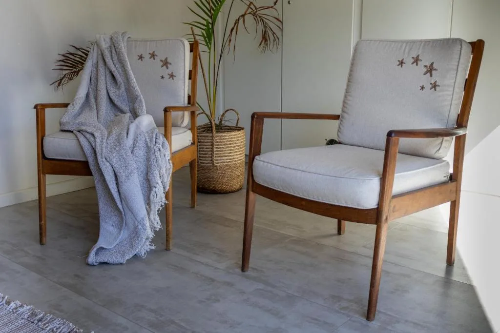 Two wooden armchairs with pale cushions and star-patterned pillows in bright lounge room