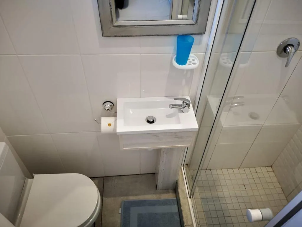 Clean bathroom with toilet, compact sink, and shower enclosure