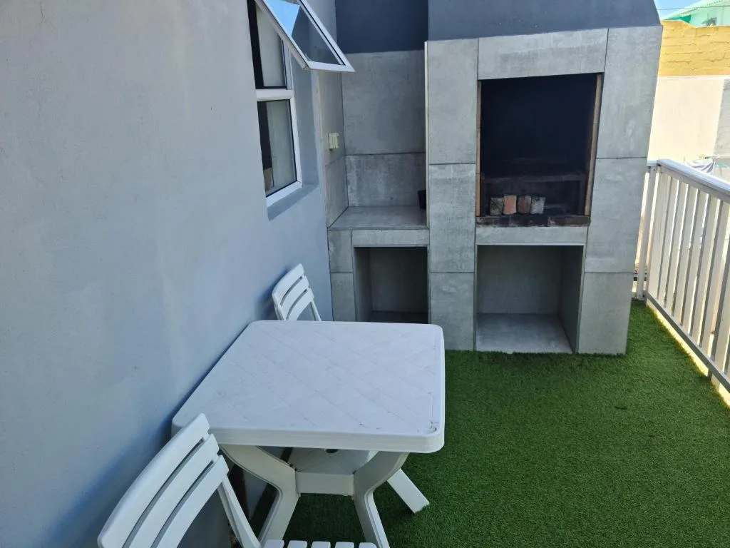 Outdoor patio area with white table, chairs, and artificial turf