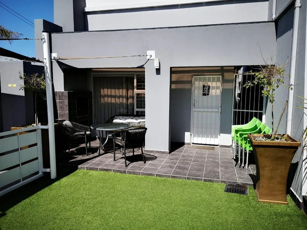 Modern patio with artificial grass, seating area, and retractable shade awning