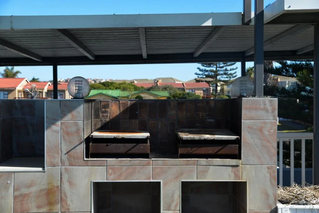 Built-in braai with metal grates and residential neighborhood background