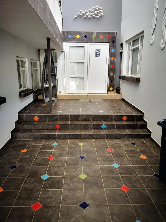 Colorful tiled entrance courtyard with white double doors and decorative fish sculpture
