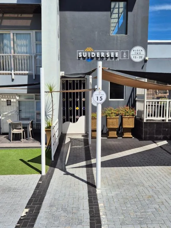 Modern black and white building entrance with signage and potted plants