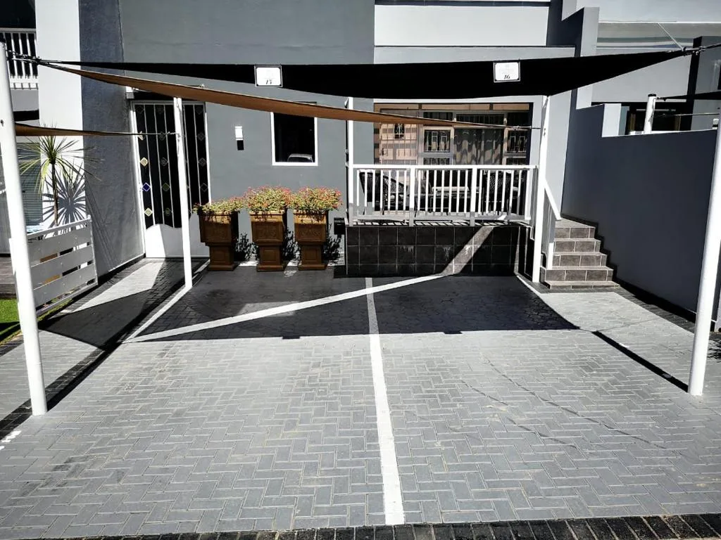 Modern apartment building entrance with paved driveway and potted plants