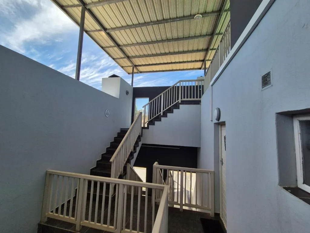 Modern apartment building exterior with stairs, railings, and covered walkway