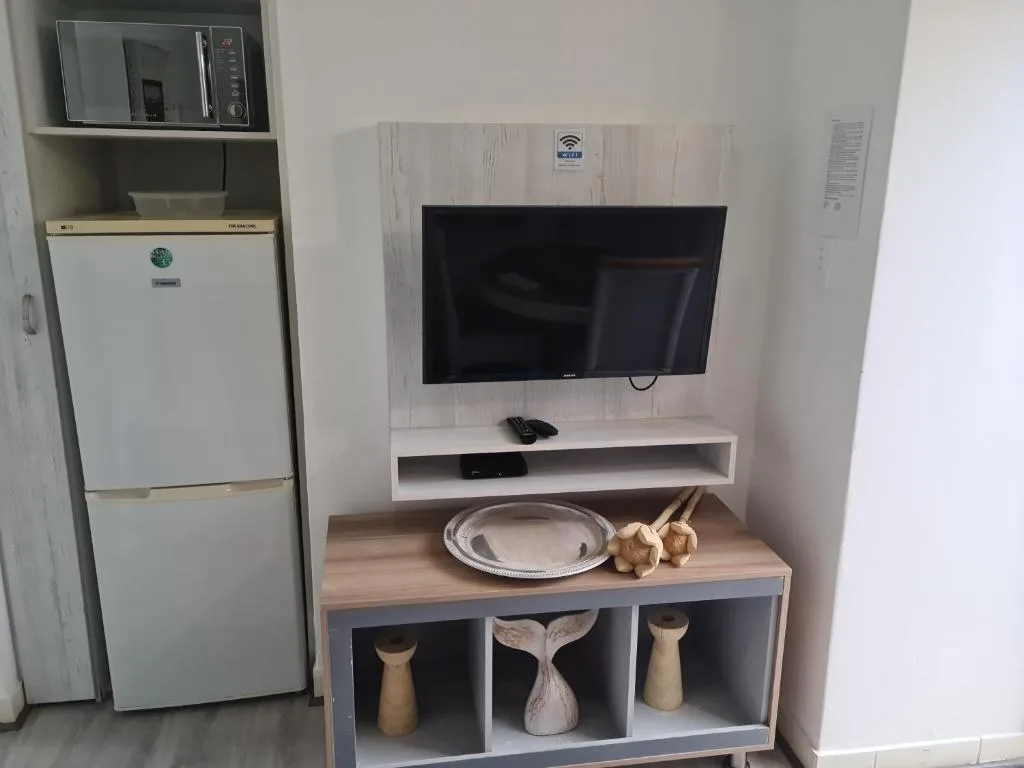 Modern lounge area with wall-mounted TV, refrigerator, and decorative storage unit
