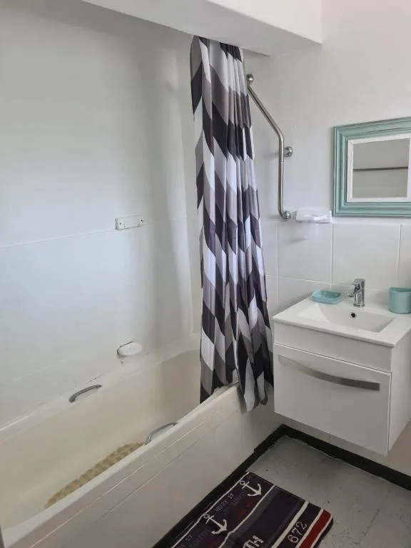 Clean bathroom with bathtub, sink vanity, and geometric shower curtain
