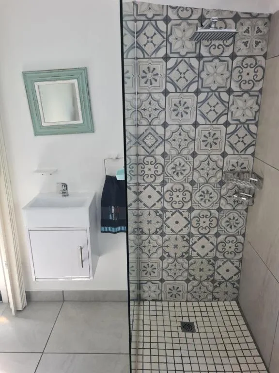 Modern bathroom with patterned tile shower and white vanity sink