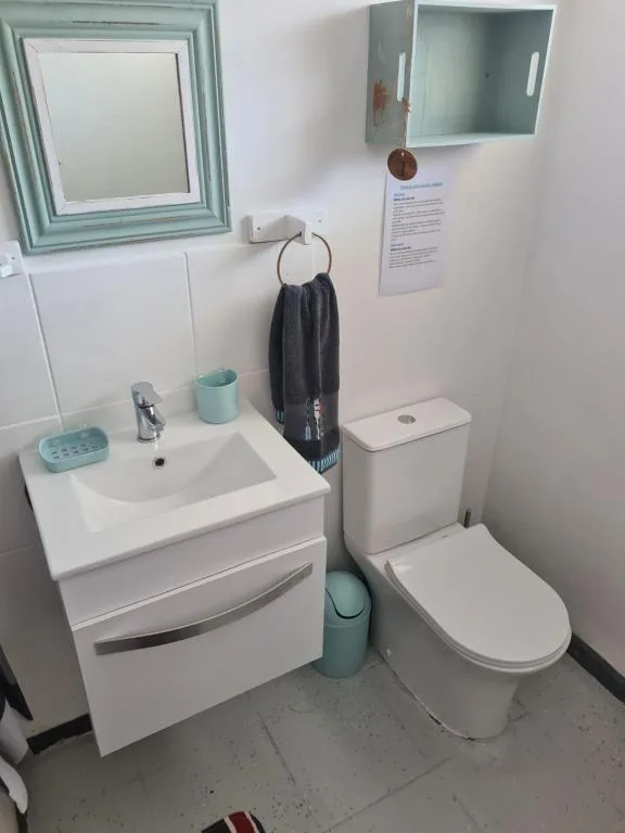 Compact bathroom with white vanity, sink, toilet, and framed mirror
