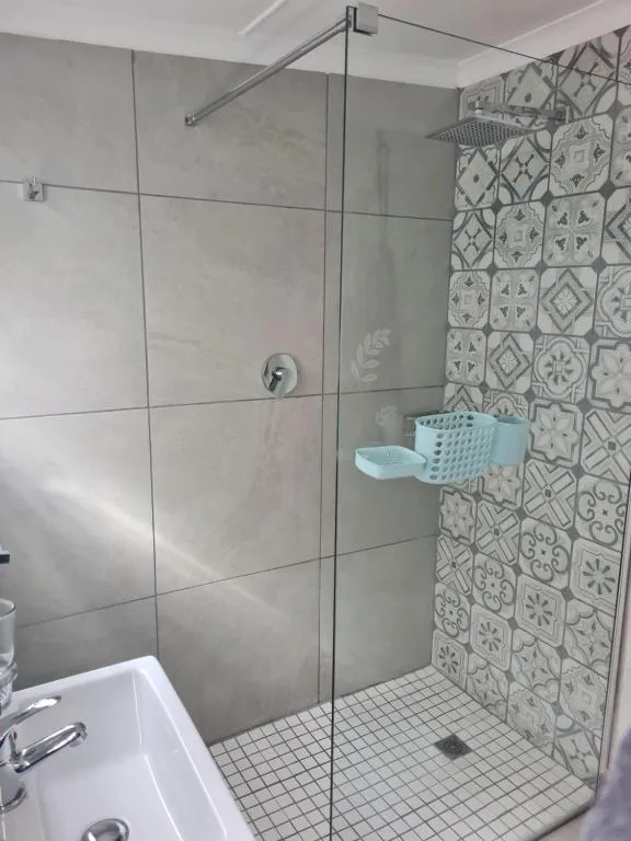 Modern walk-in shower with glass enclosure and patterned feature tiles