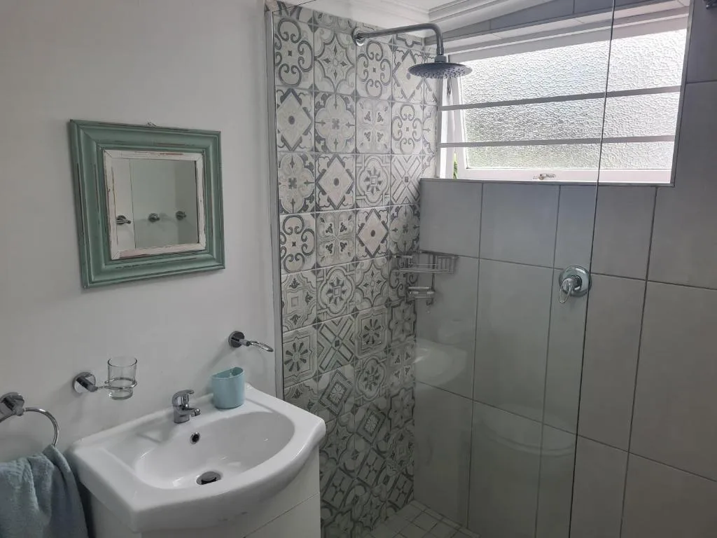 Modern bathroom with patterned tile shower and white sink vanity
